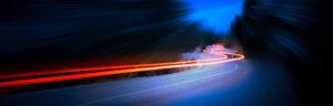 Langzeitbelichtungsbild von Autobeleuchtung in einer Gebirgsstraße bei Nacht.