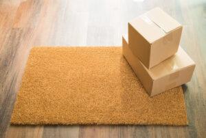 Fußmatte auf Holzboden mit Kartons darauf.