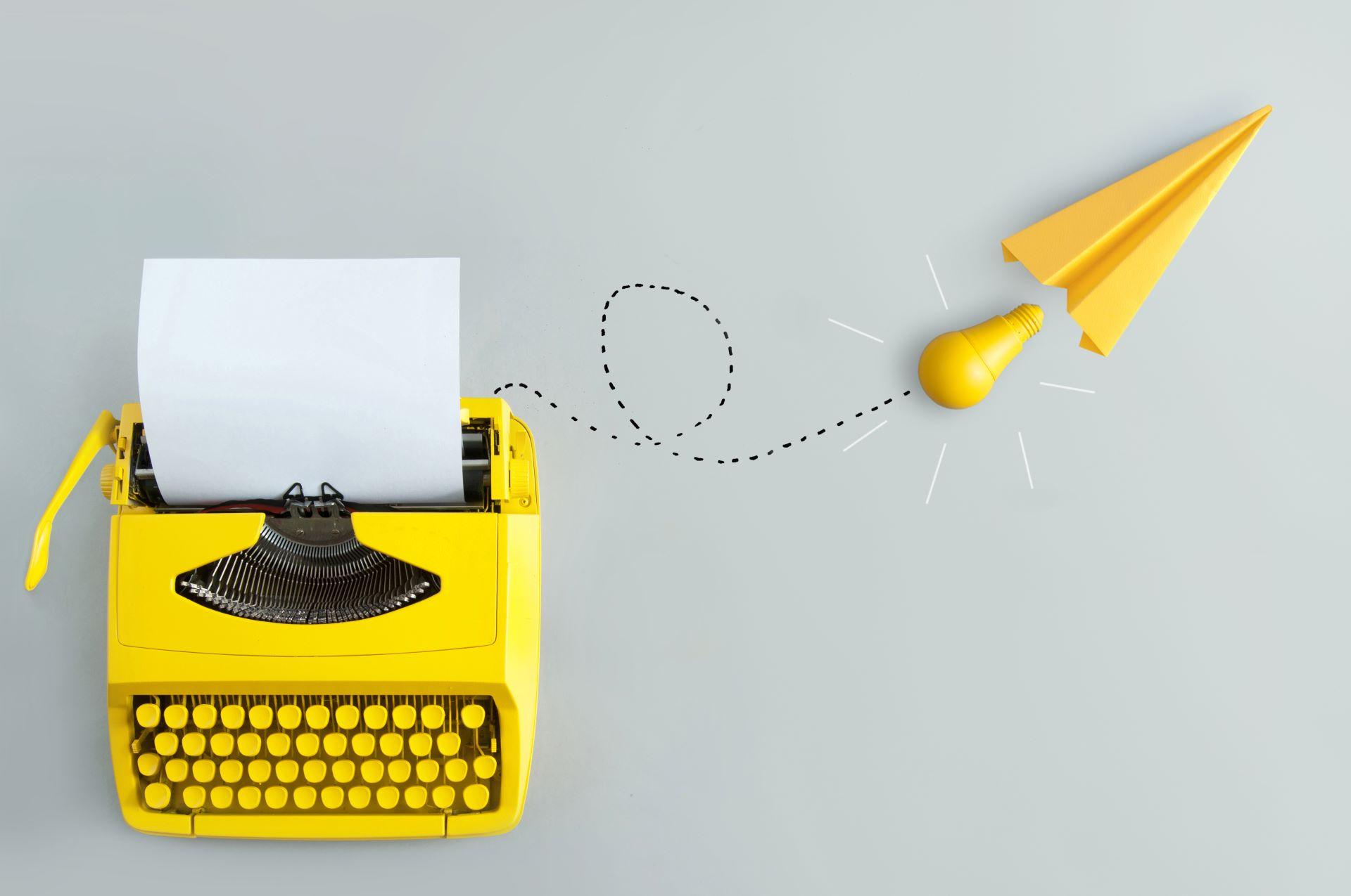Gelbe Schreibmaschine mit Papier und Papierflieger als Buch Lektorat Symbol