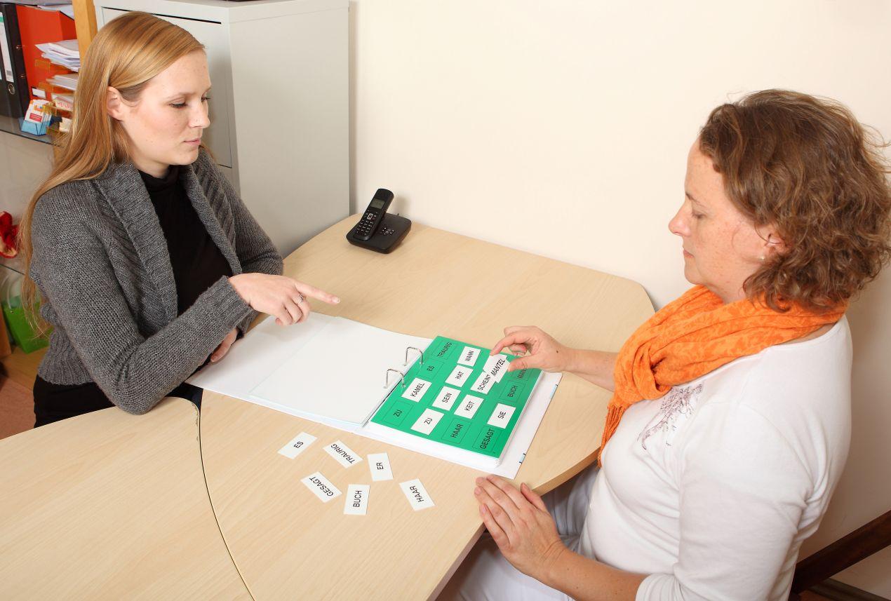 Eine Therapeutin arbeitet mit einer erwachsenen Patientin an Sprachuebungen mit Wortkarten in der Logopaedie Herdecke.